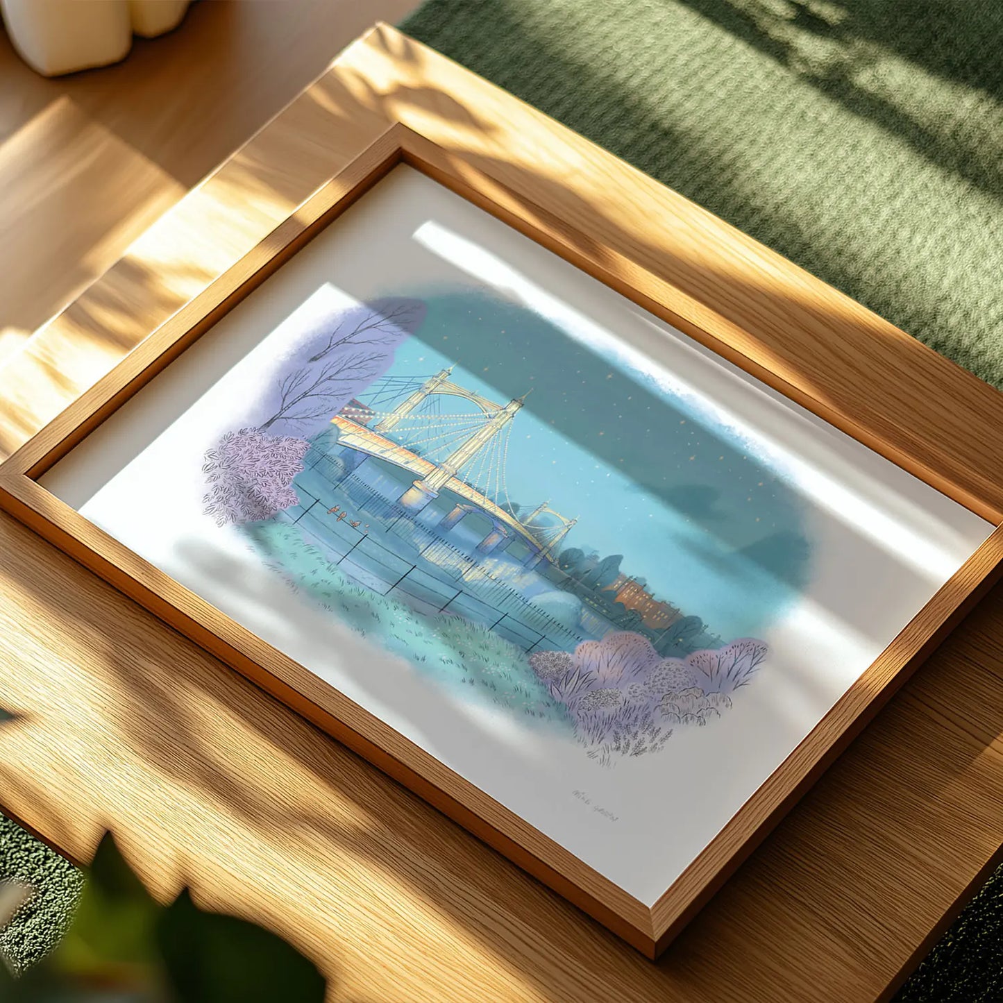 Framed print in sunlight of a painting of Albert Bridge on the Thames seen from Battersea Park in London by Mike Green Illustration