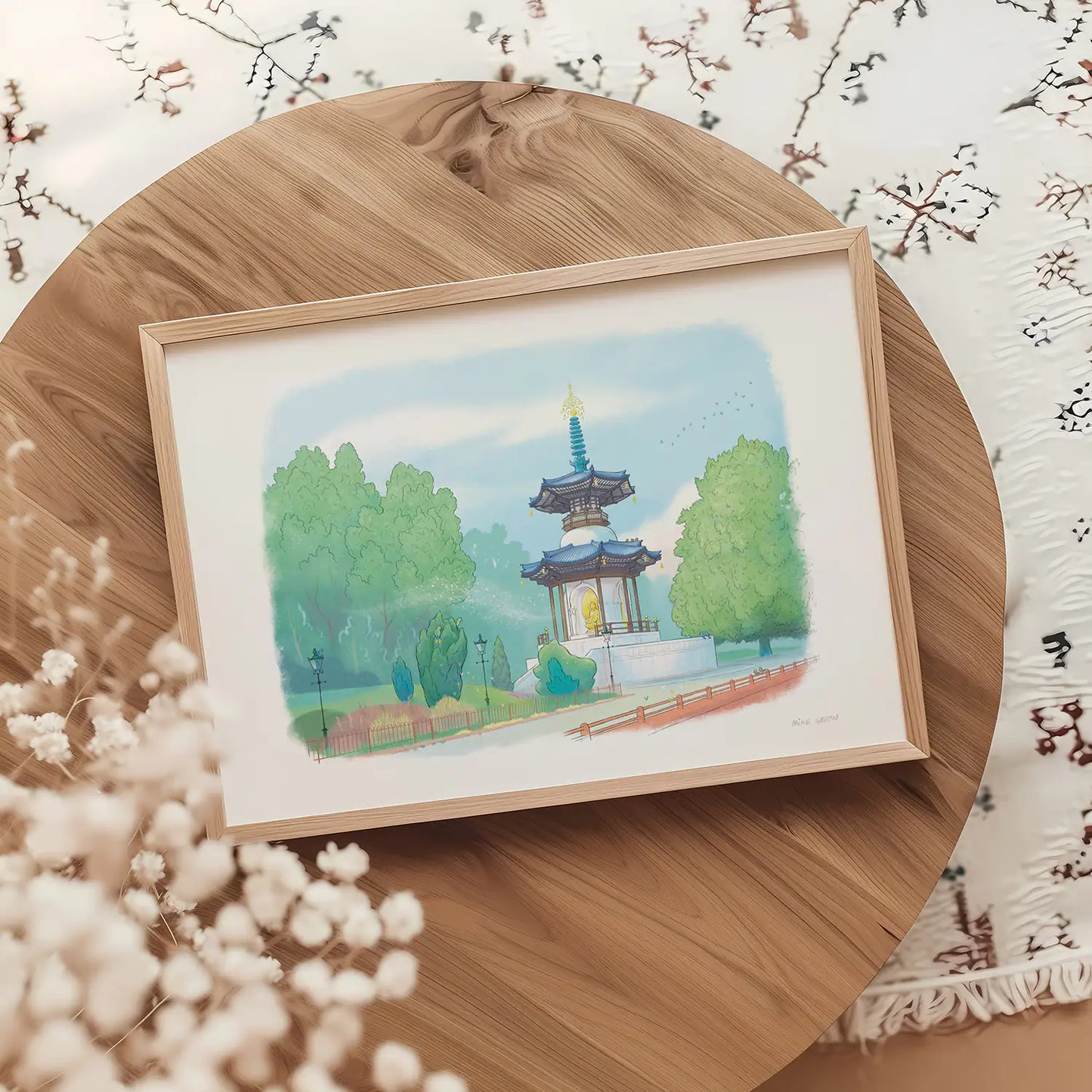 Framed print on a table of a painting of Battersea Parks Peace Pagoda in London by Mike Green Illustration