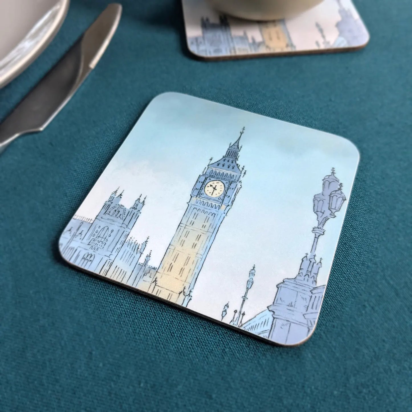Square coaster with a painting of London's Big Ben at night on a blue tablecloth
