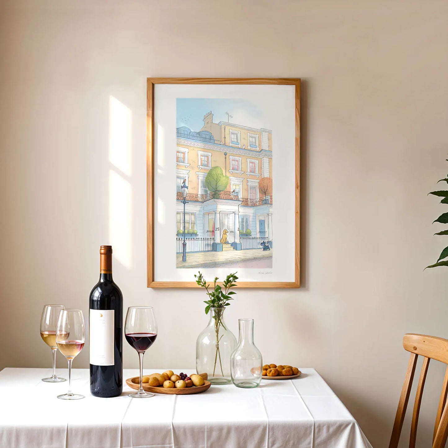 Framed print of a painting with one dog visiting another on a street in London's Kensington framed on a wall with wine on a table