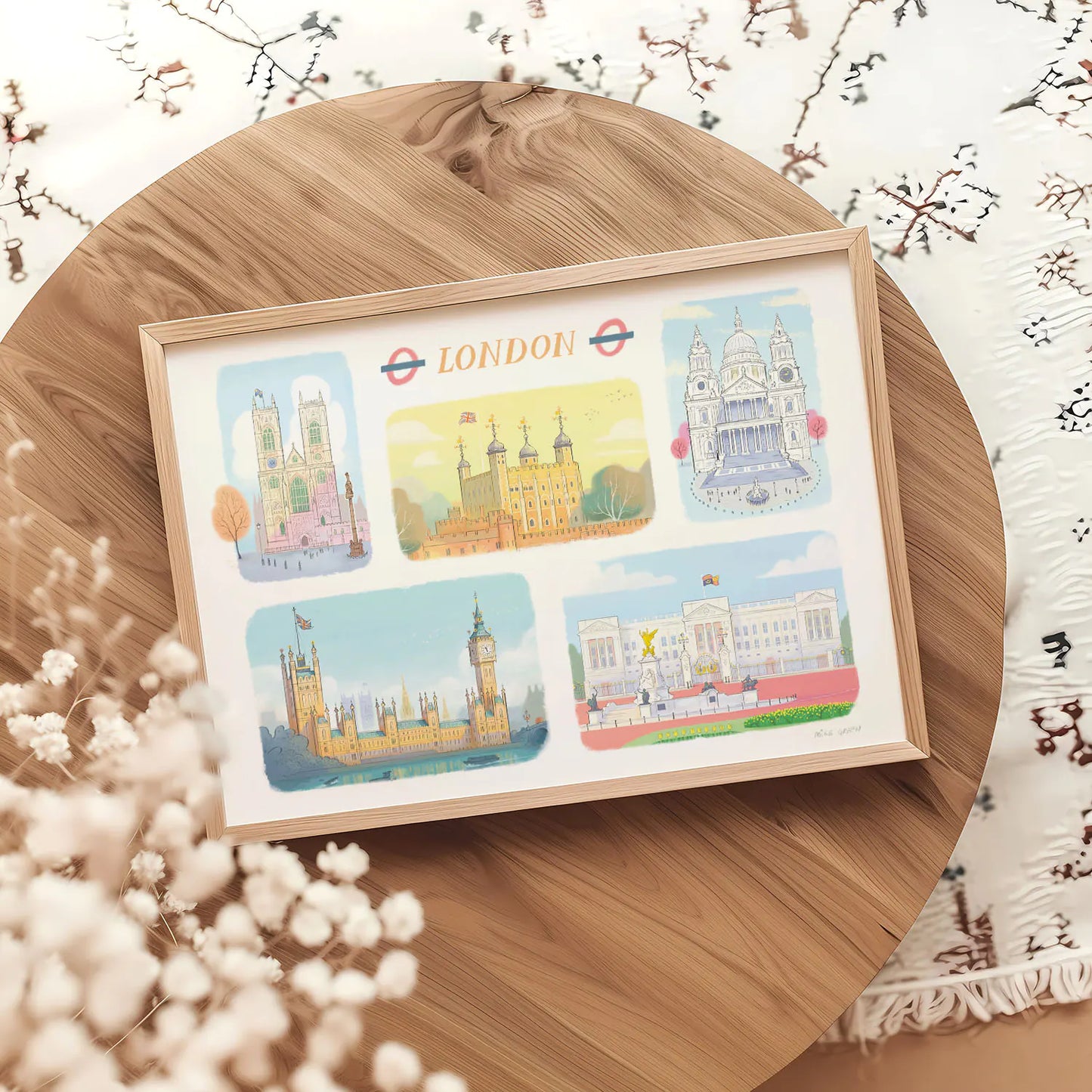 A framed art print of London's landmarks including, Westminster Abbey, The Tower of London, St Paul's Cathedral, Palace of Westminster and Buckingham Palace on a round table