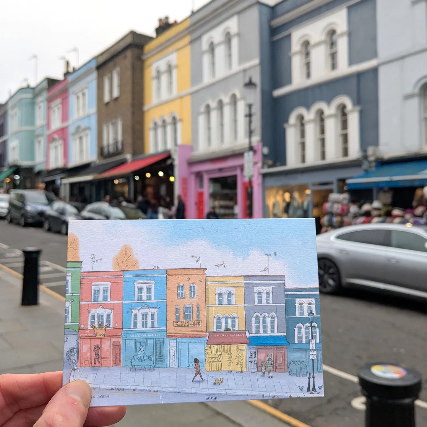 Greetings card of Portobello road in London's Notting Hill held in front of shops.