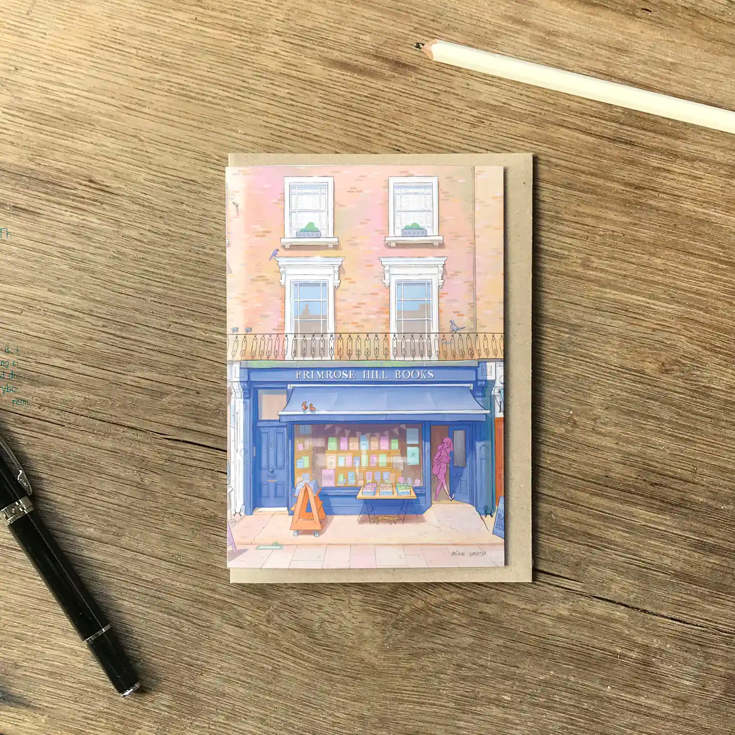 Greetings card with an illustration of London's Primrose Hill Books on a wooden surface with pencil and pen