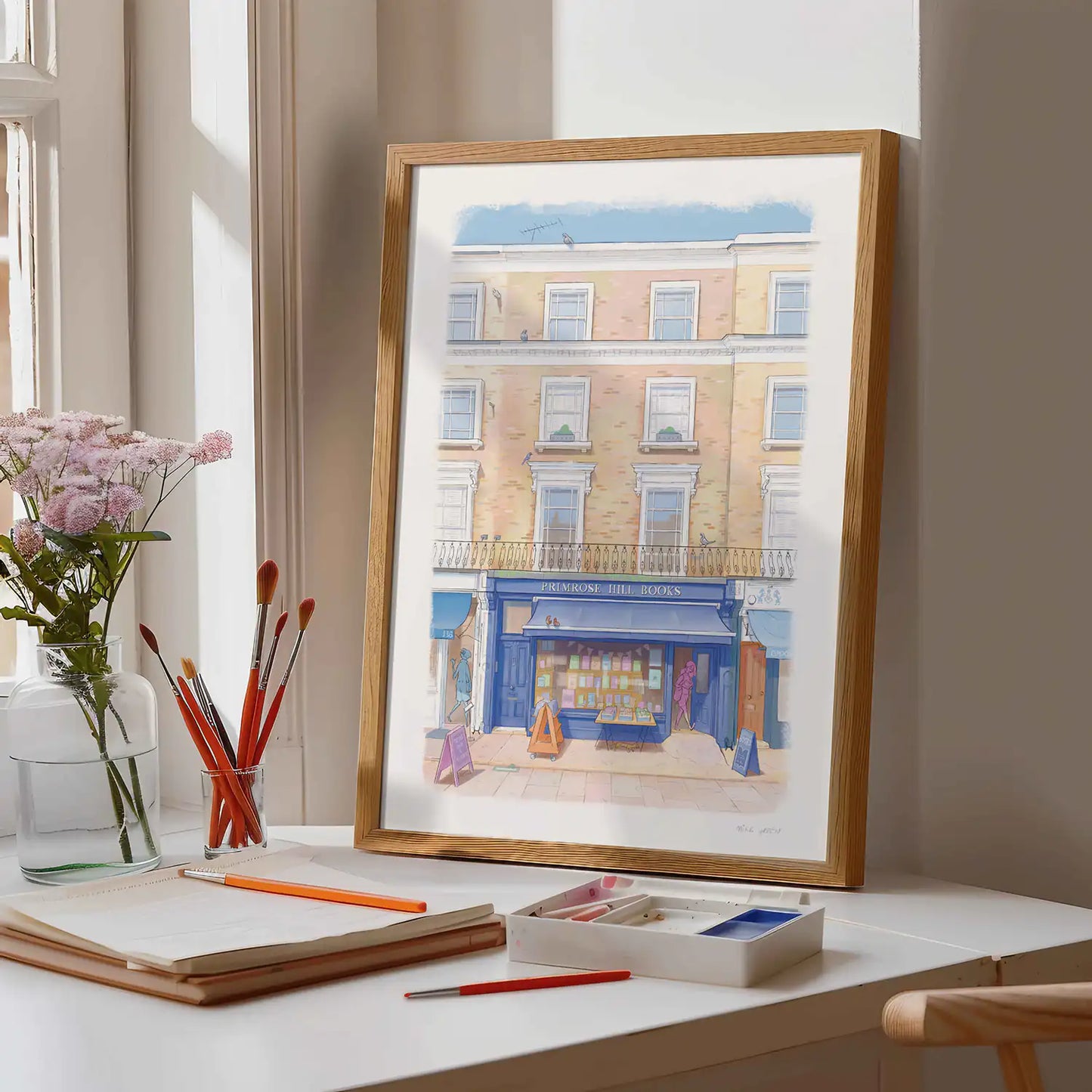 Framed print of the Notting Hill Bookshop London illustrated by Mike Green Illustration on a desk