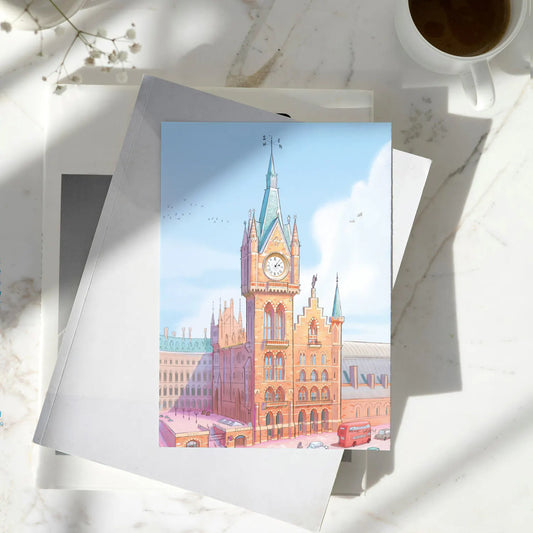 Greetings card with painting of St Pancras International Railway Station in London by Mike Green Illustration sitting on a pile of books on a marble table