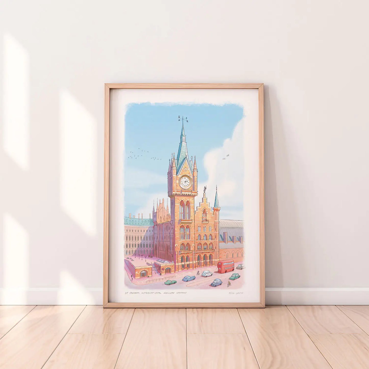 Framed art print of a painting of St Pancras International Railway Station in London by Mike Green Illustration next to a lamp