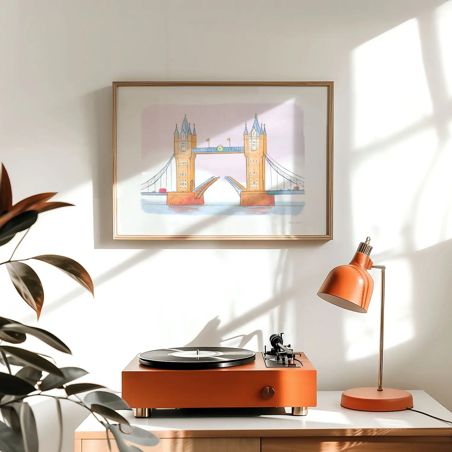 Framed wall art print of London's Tower Bridge above a record player and lamp