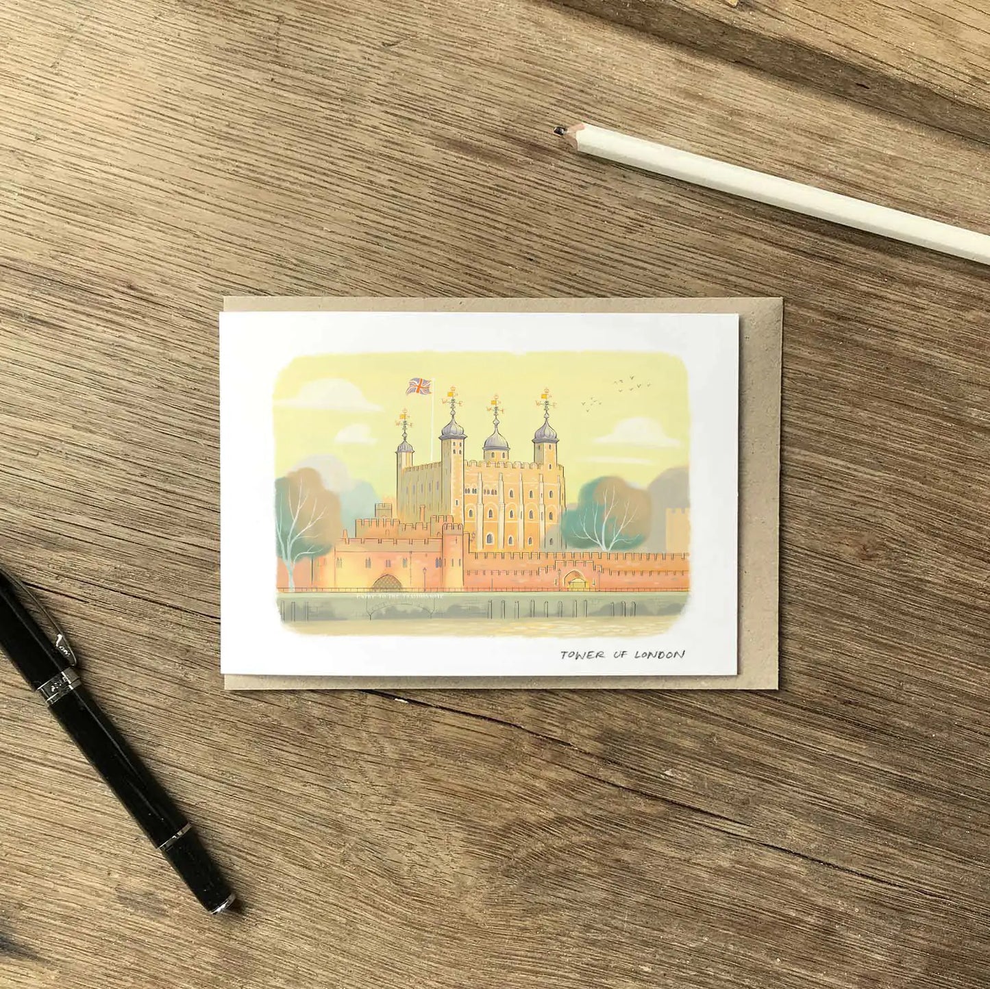 Greetings card with the an illustration of Tower of London on a wooden table with pencil and pen.