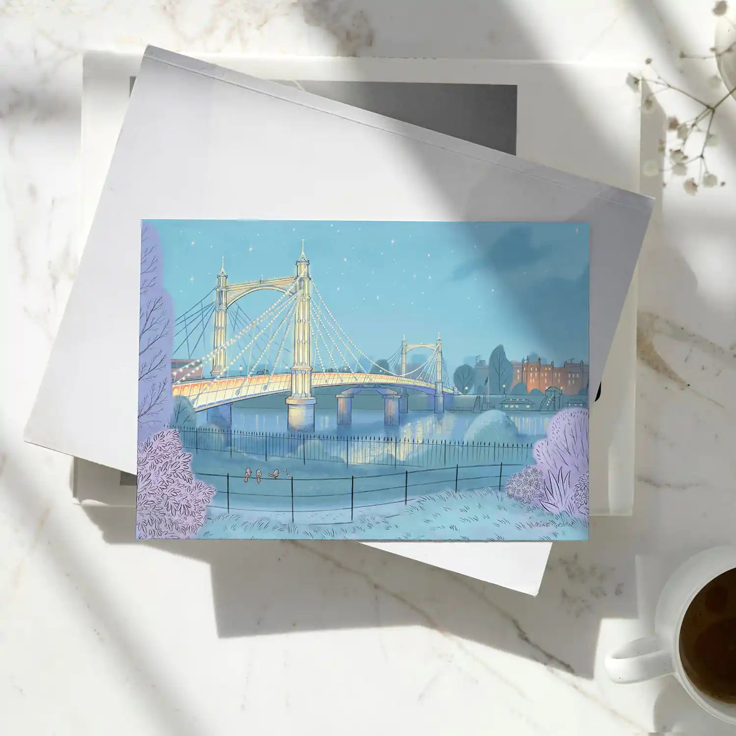 Greetings card of Albert Bridge on the Thames London painted by Mike Green Illustration sitting on a pile of books