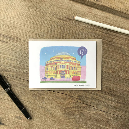 London's Royal Albert Hall illustrated on a greeting card with an envelope and pencil on wooden surface