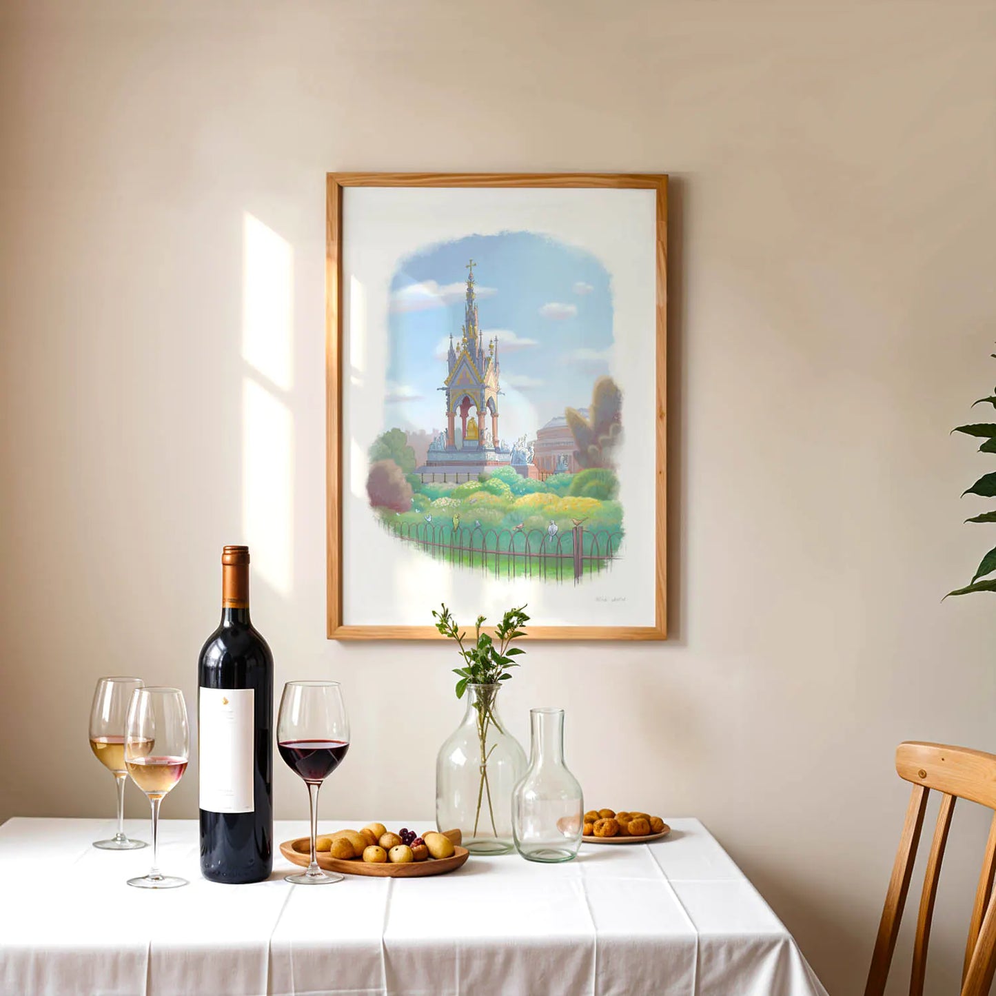 Framed wall art print of a painting of the Albert Memorial in London Hyde Park hanging above a table with wine and fruit