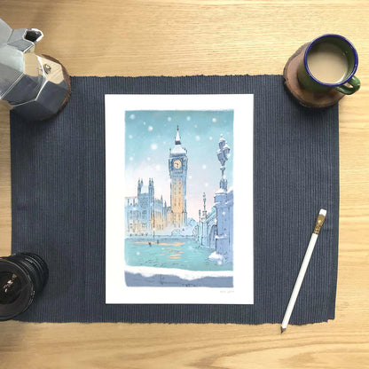 London's big ben in the snow wall art print with a coffee and pencil on a desk