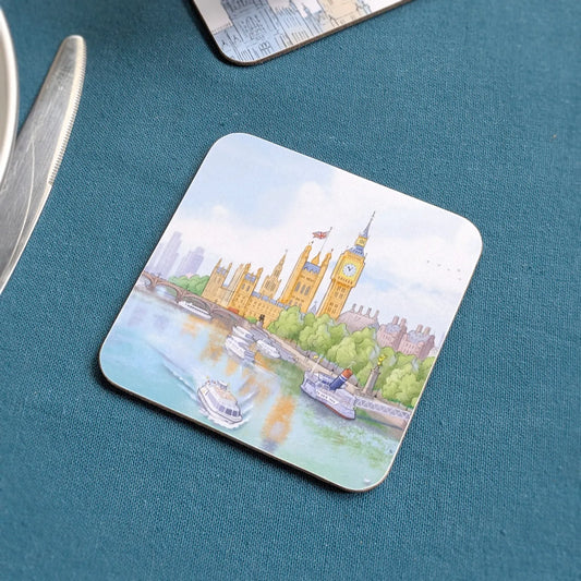 A square coaster with rounded corners featuring a watercolor-style painting of Big Ben and Westminster Palace in London by the Thames, placed on a textured teal surface.