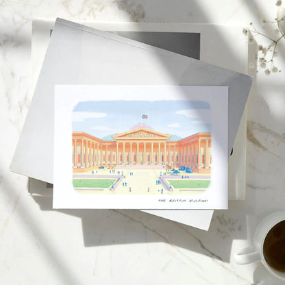 Greetings card of The British Museum in London on a pile of books on a marble table with a coffee cup