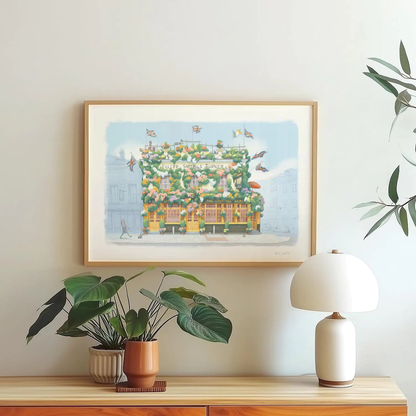 Wall art print of a painting of The Churchill Arms pub in Kensington London framed above plants