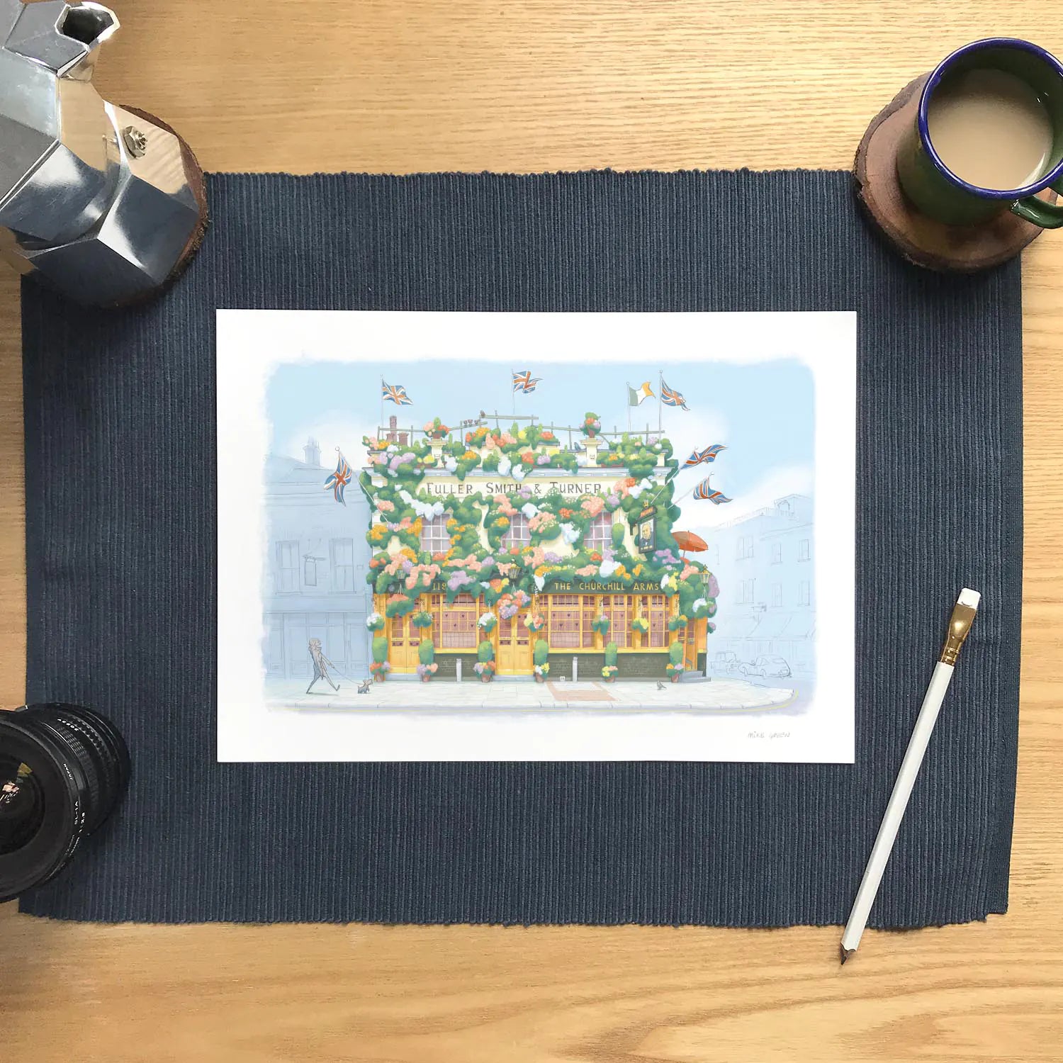 Wall art print of a painting of The Churchill Arms pub in Kensington London with pencil and coffee cup