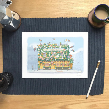 Wall art print of a painting of The Churchill Arms pub in Kensington London with pencil and coffee cup