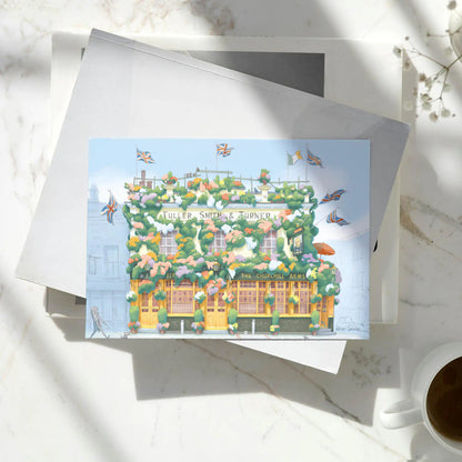 Greetings card of a painting of The Churchill Arms pub in west London's Kensington near Notting Hill on a pile of books