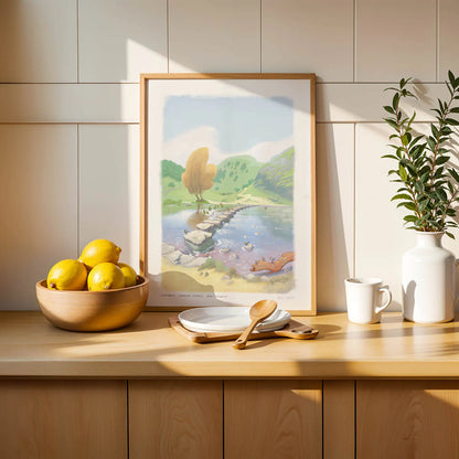 Framed wall art print of a painting of the stepping stones in Dovedale in the Peak District national park on a shelf with lemons
