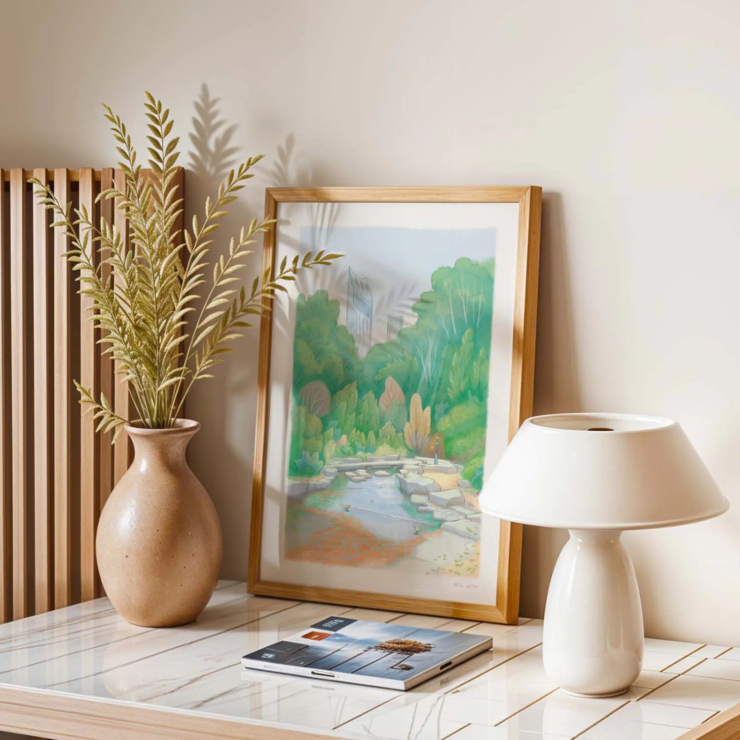 Framed wall art print of a painting of Elephant Park in London's Elephant and Castle on a table with a lamp