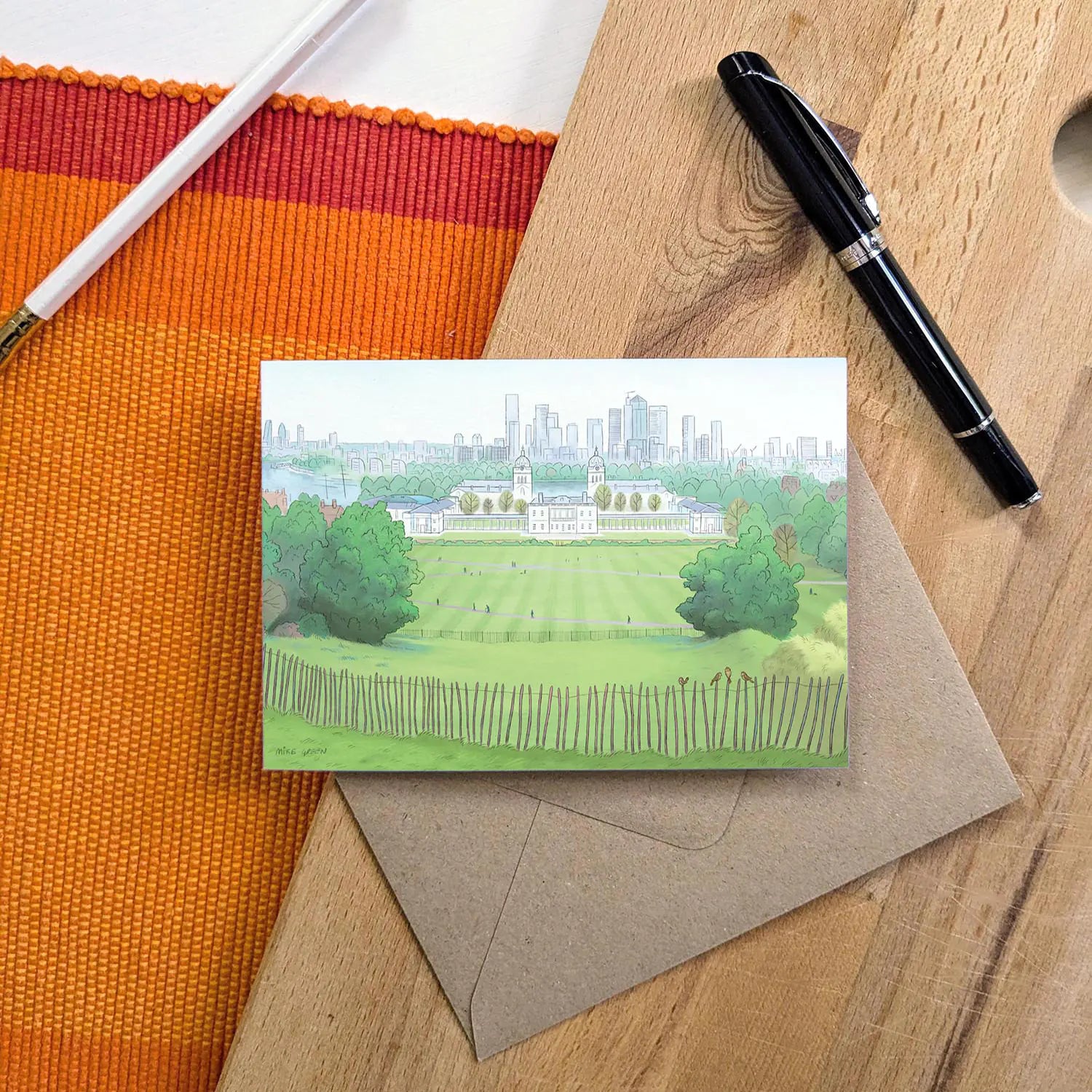 Greetings card with painting of the view from London's Greenwich Park with an envelope and pencil on a wooden surface