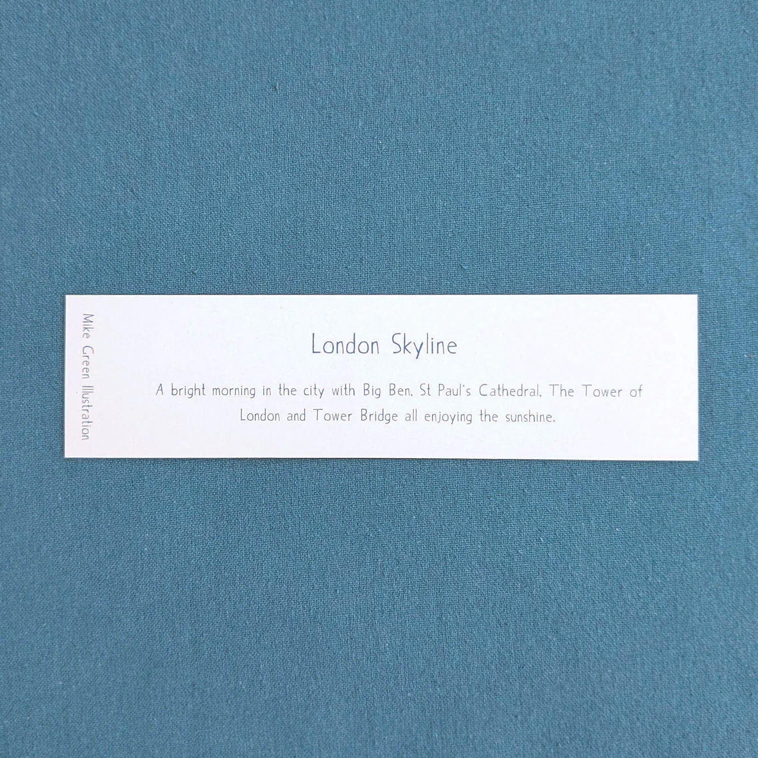 Text on the back of a bookmark with London city landmarks in the sunshine including Big Ben St Paul's Cathedral