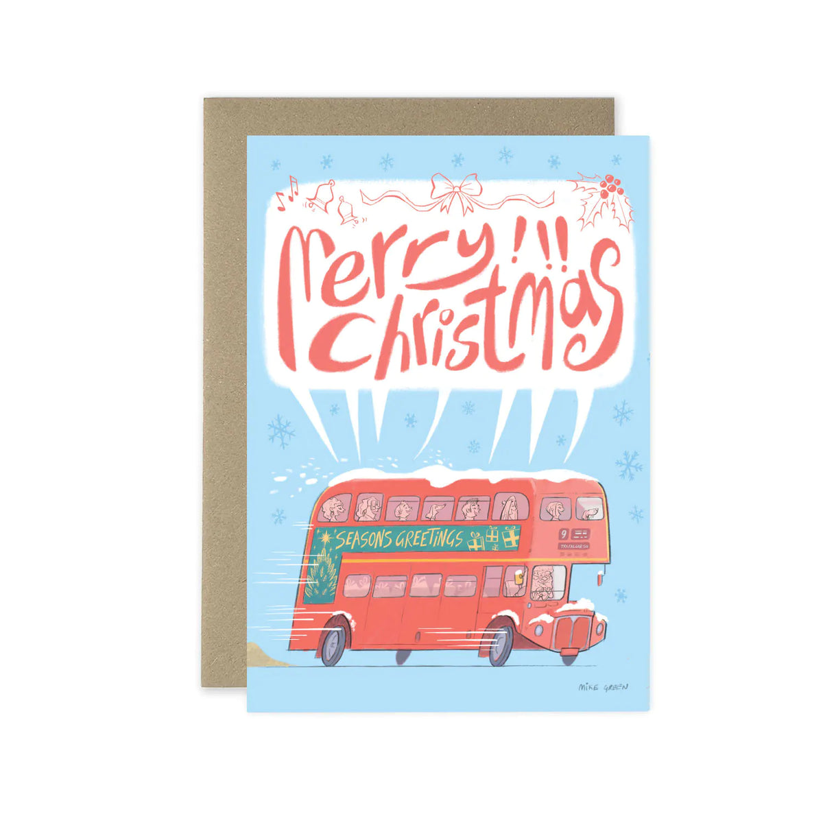 A Christmas greeting card with a kraft envelope behind it. The card features a light blue background, red hand-lettered text reading 'Merry Christmas,' and an illustration of a red double-decker bus with snow on top and 'Season's Greetings' written on the side.