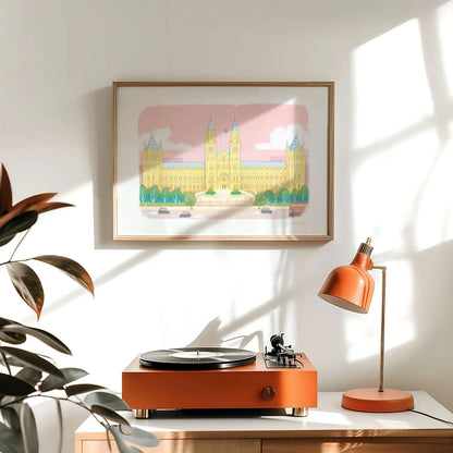 Framed wall art print of the Natural History Museum in London's South Kensington above a table with a record player and lamp