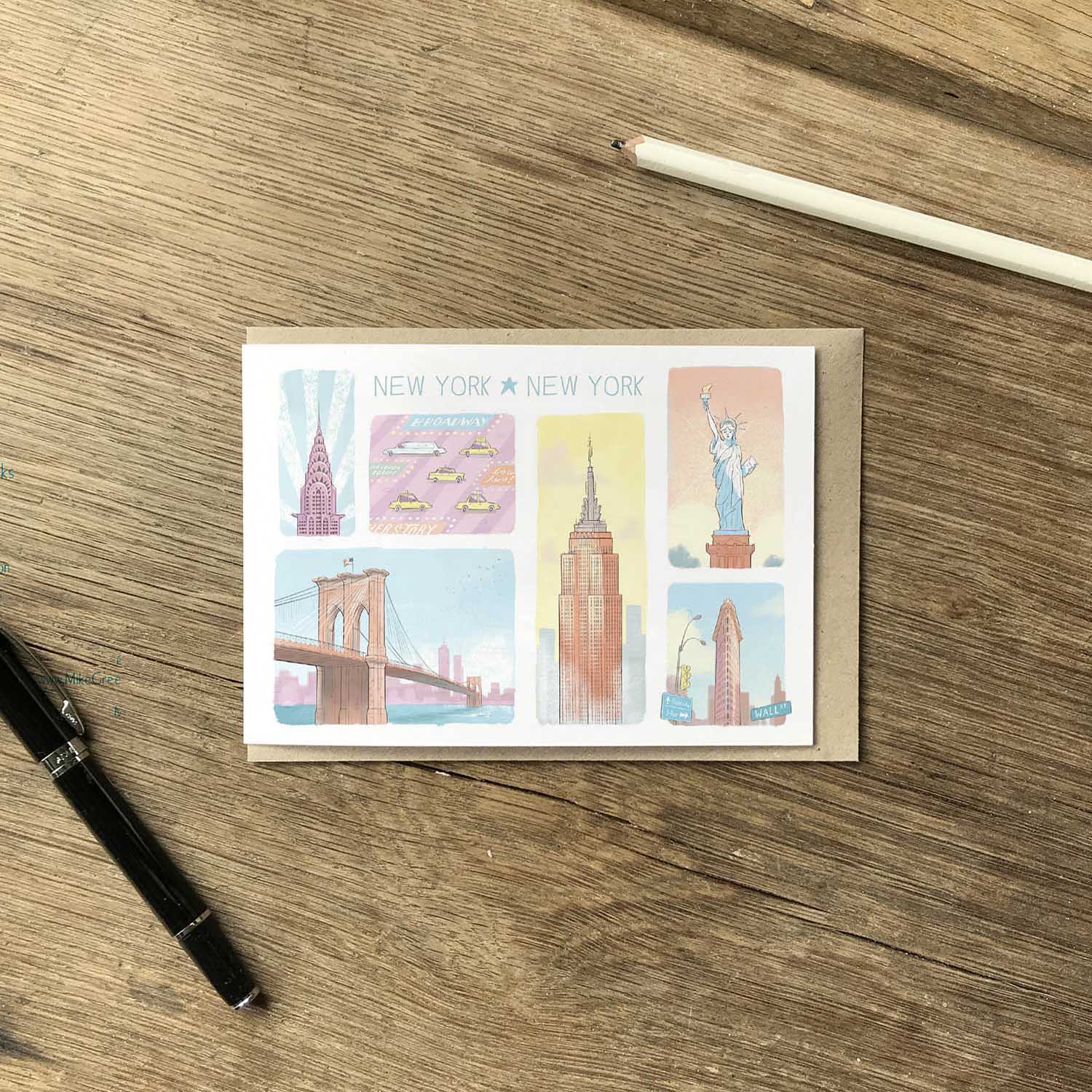 Greetings card with New York's landmarks in pastel colours on a wooden surface with a pen and pencil
