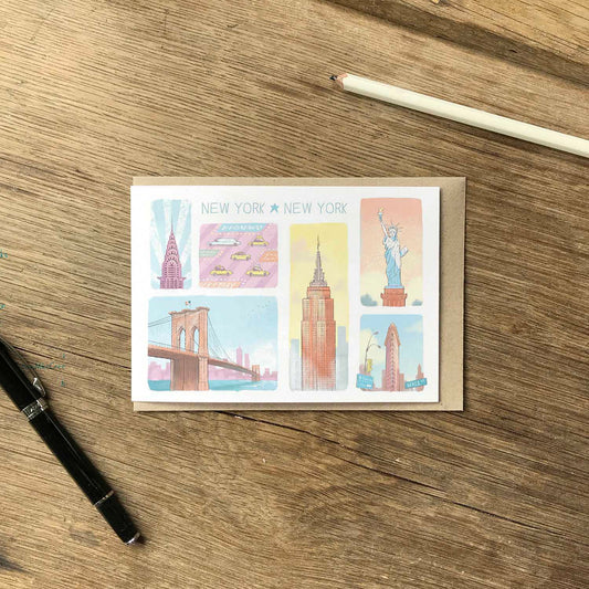Greetings card with New York's landmarks in pastel colours on a wooden surface with a pen and pencil