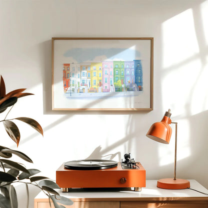 Framed wall art print of a painting of Colourful town Houses on Lancaster road in London's Notting Hill, hanging above a record player and lamp
