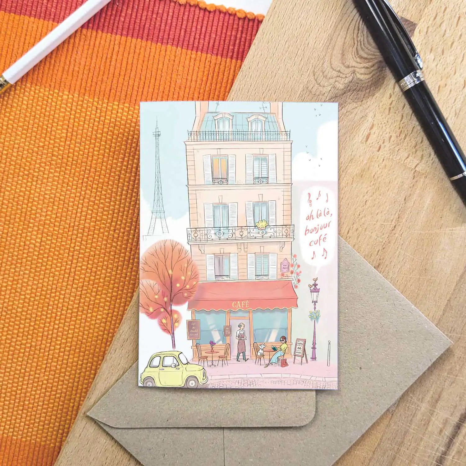 Paris cafe with lady and dog and bonjour cafe text beautifully illustrated on a greeting card by mike green illustration.