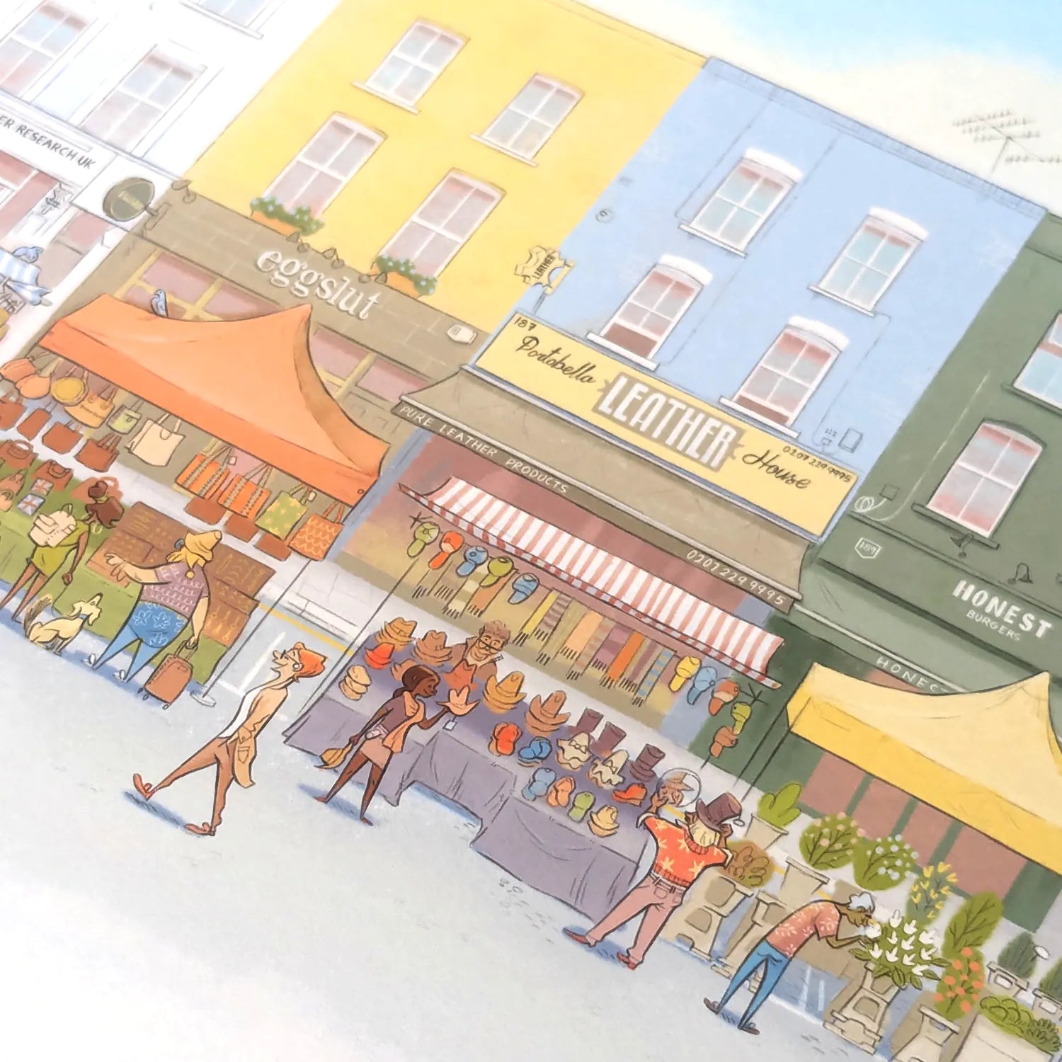 Wall art print of a pastel watercolor illustration of Portobello Road Market in London's Notting Hill with colorful buildings, storefronts, pedestrians, and market stalls.