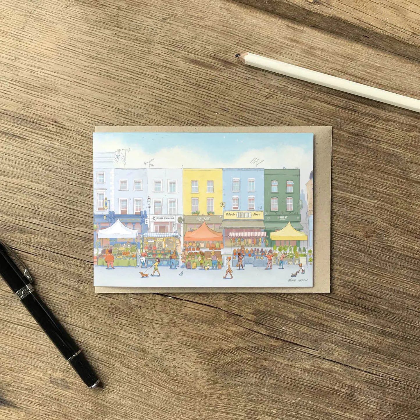 A greetings card of the Portobello Road Market in London's Notting Hill with an envelope and pencil on a wooden surface