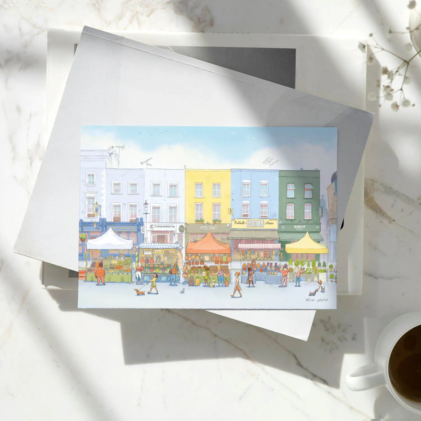 A greetings card of the Portobello Road Market in London's Notting Hill on a pile of books on a marble surface