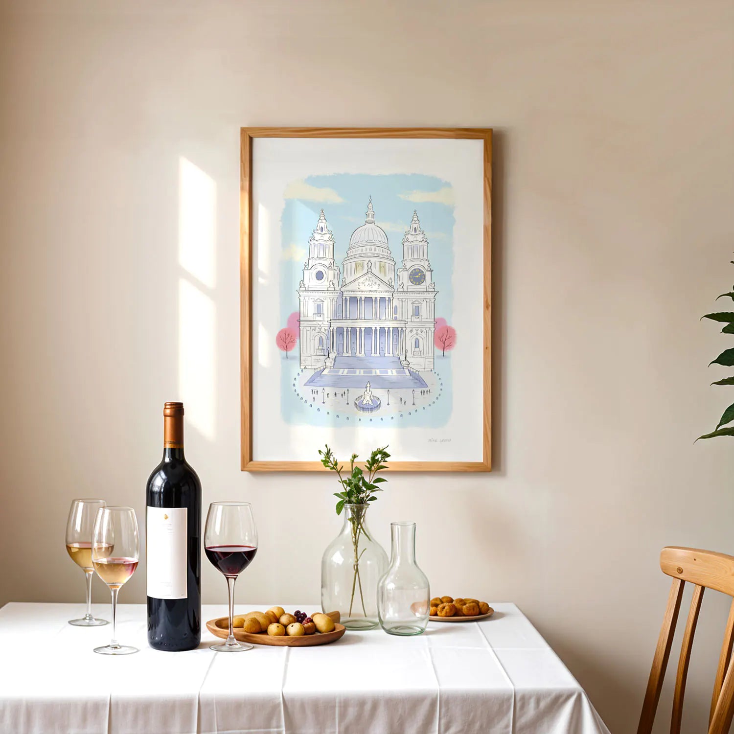 Framed print of London's St Pauls Cathedral illustration framed above a table with a wine bottle
