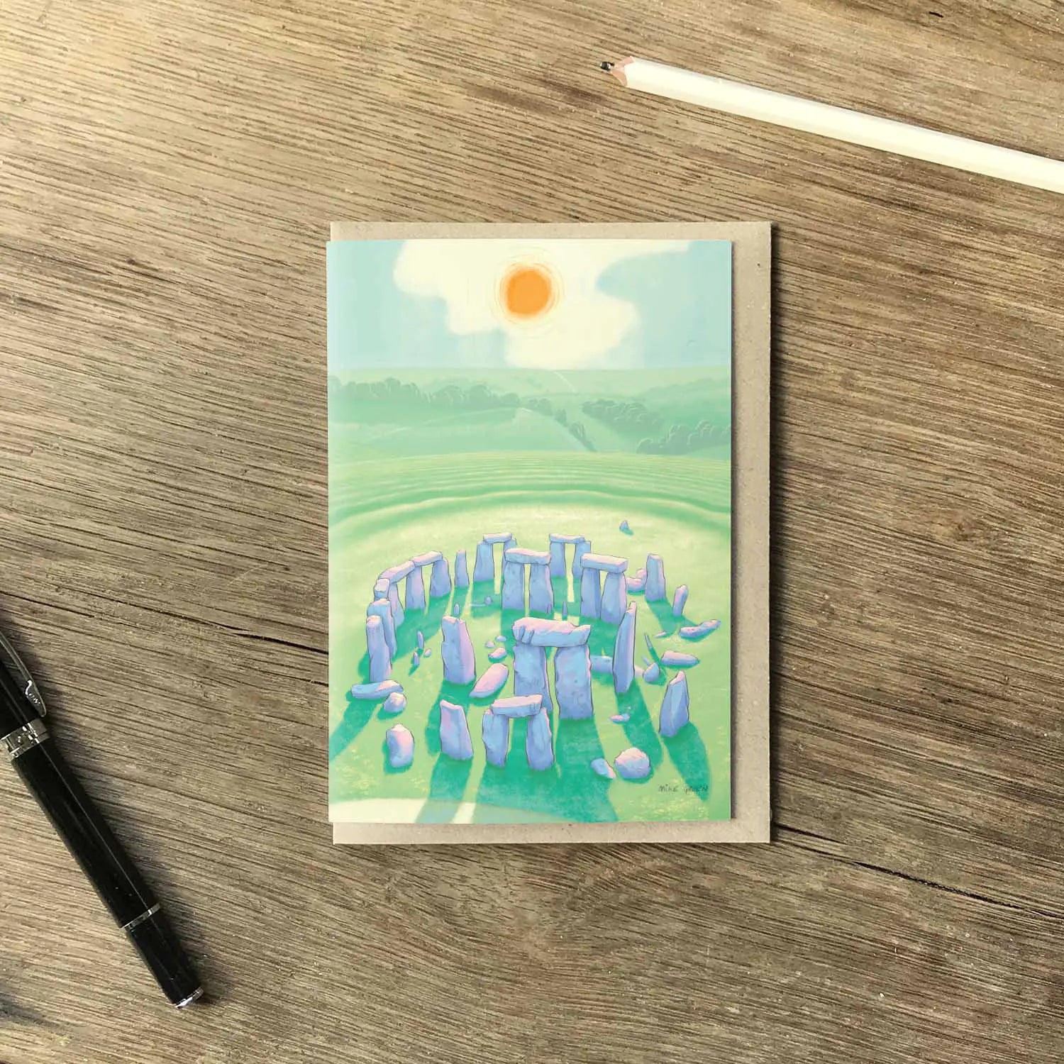 Greetings card with a painting of Stonehenge in Wiltshire England on wooden table with a pencil and pen