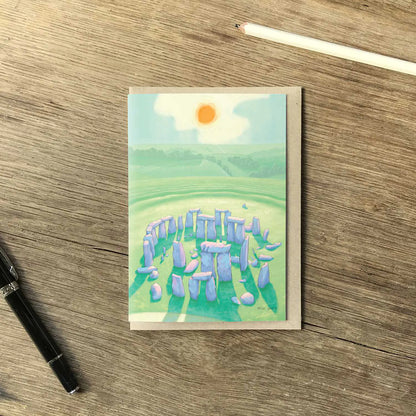 Greetings card with a painting of Stonehenge in Wiltshire England on wooden table with a pencil and pen