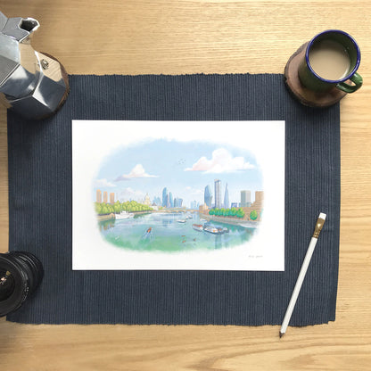 Print of a painting of the view from London's Waterloo Bridge towards St Paul's Cathedral on desk with pencil and cup of coffee.