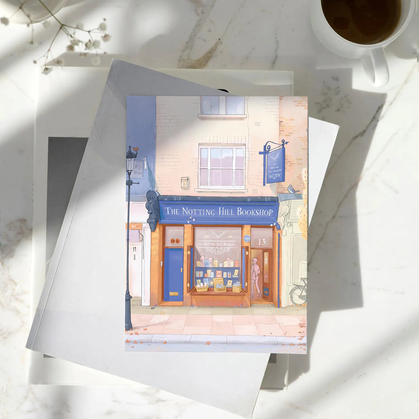 Greetings card on marble table with an illustration of London's The Notting Hill Bookshop in the Autumn