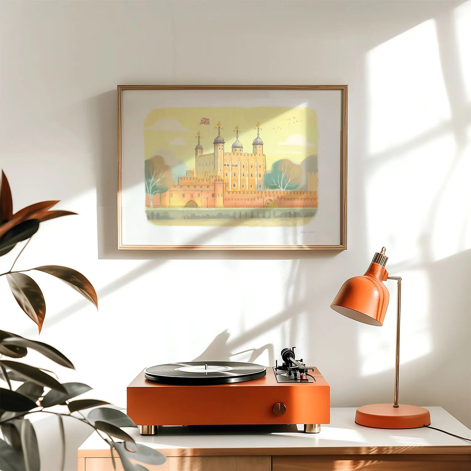 A framed art print of the Tower of London castle above a lamp and record player