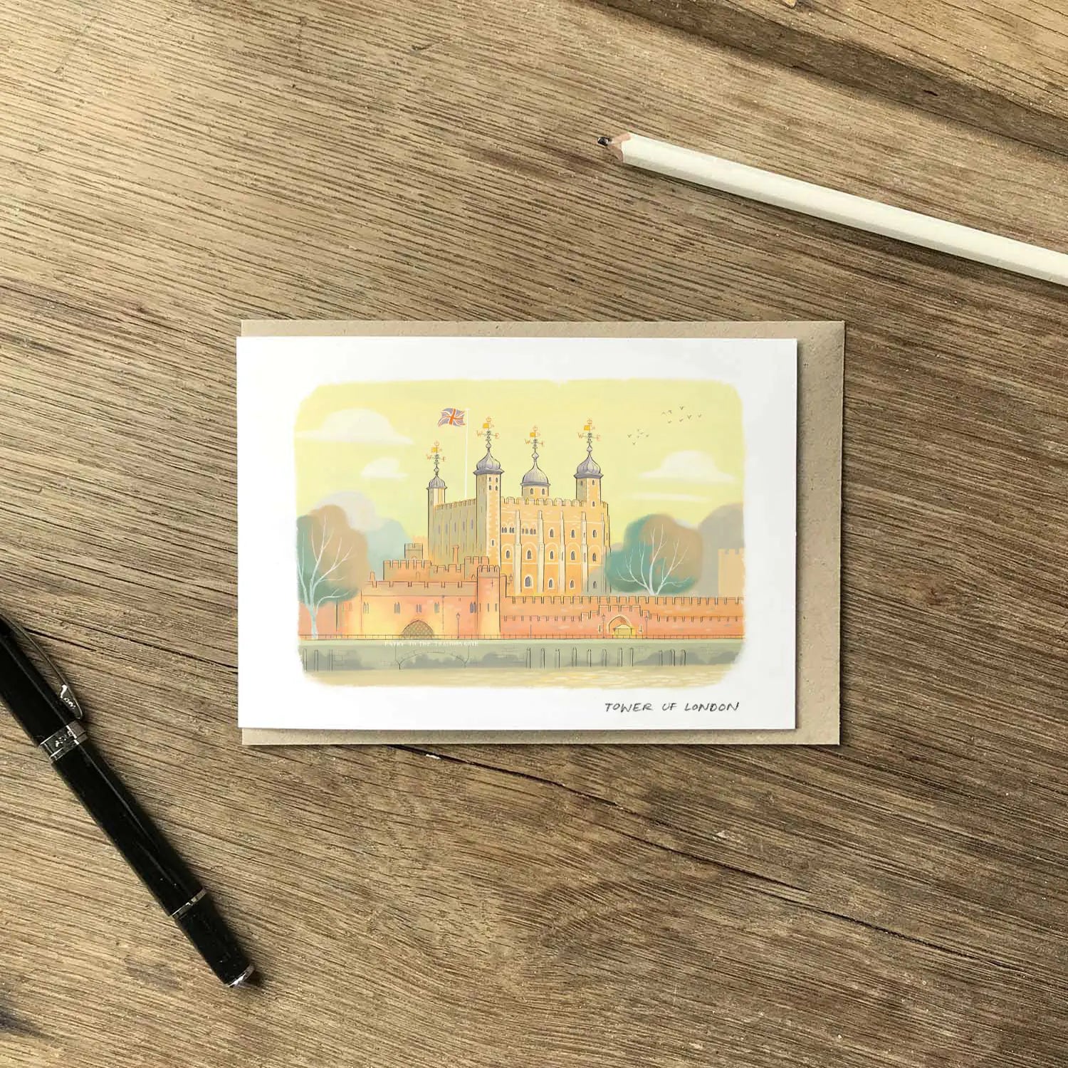 Greetings card with the an illustration of Tower of London on a wooden table with pencil and pen.