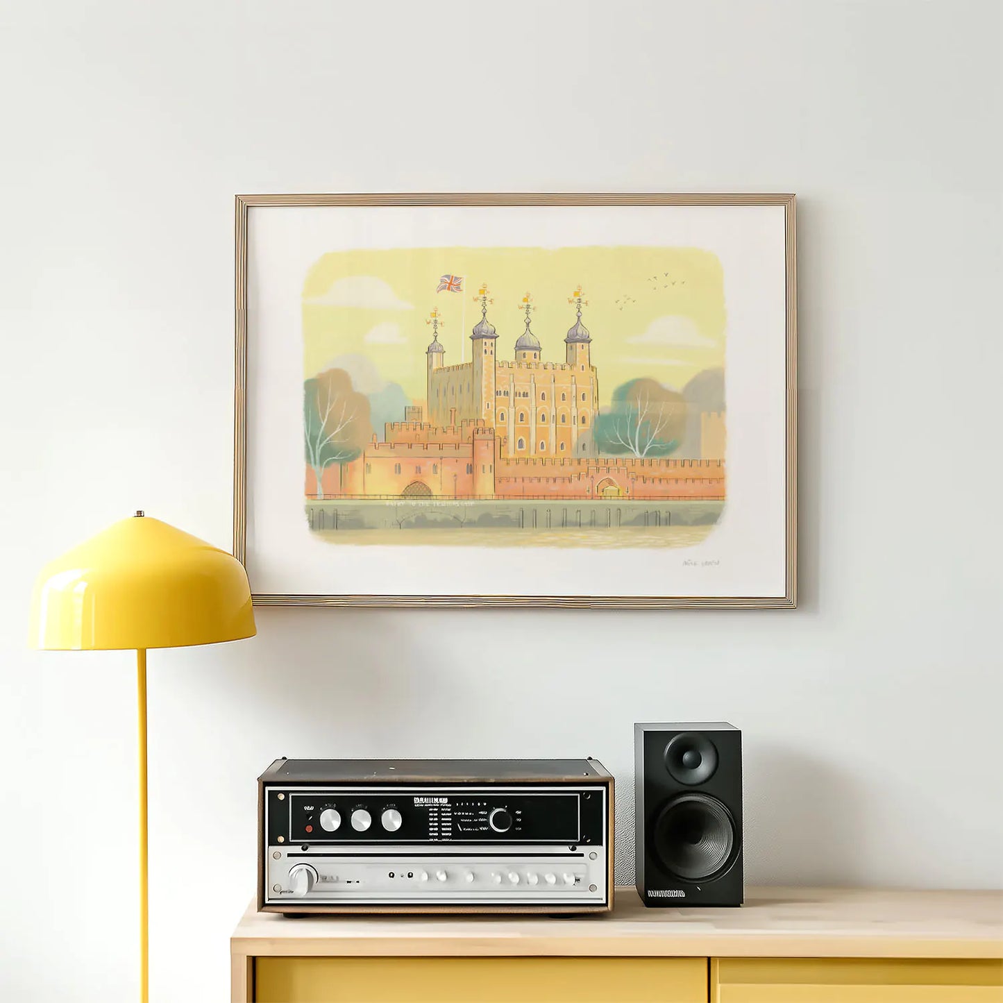 A framed art print of the Tower of London landmark above a lamp and stereo
