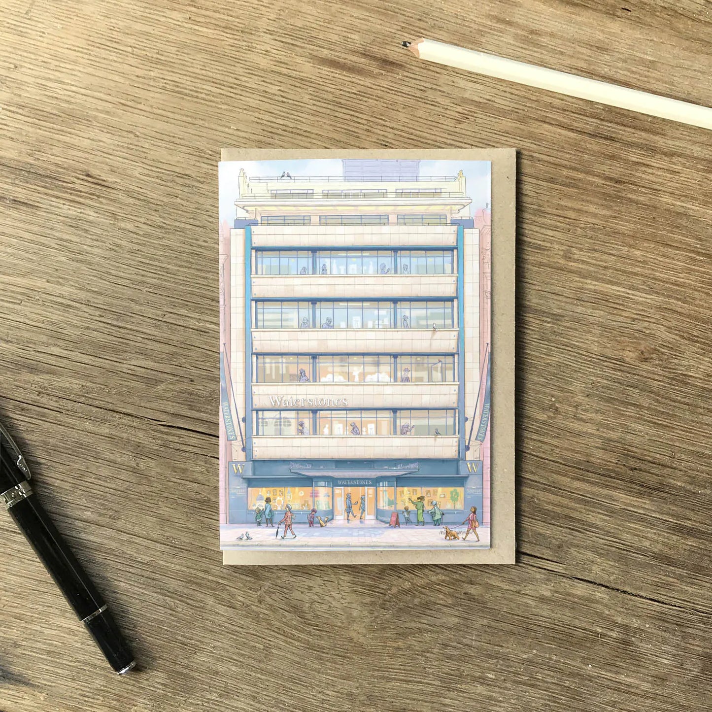 Greetings card with painting of Waterstones Piccadilly bookstore in London with an envelope and pencil on wooden surface