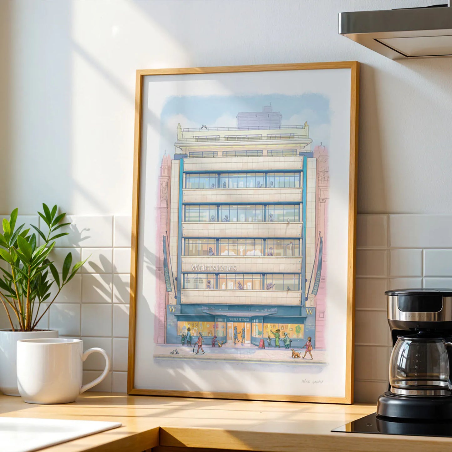 Framed wall art print of Waterstones Piccadilly bookstore in London on a kitchen side with a cup and coffee machine