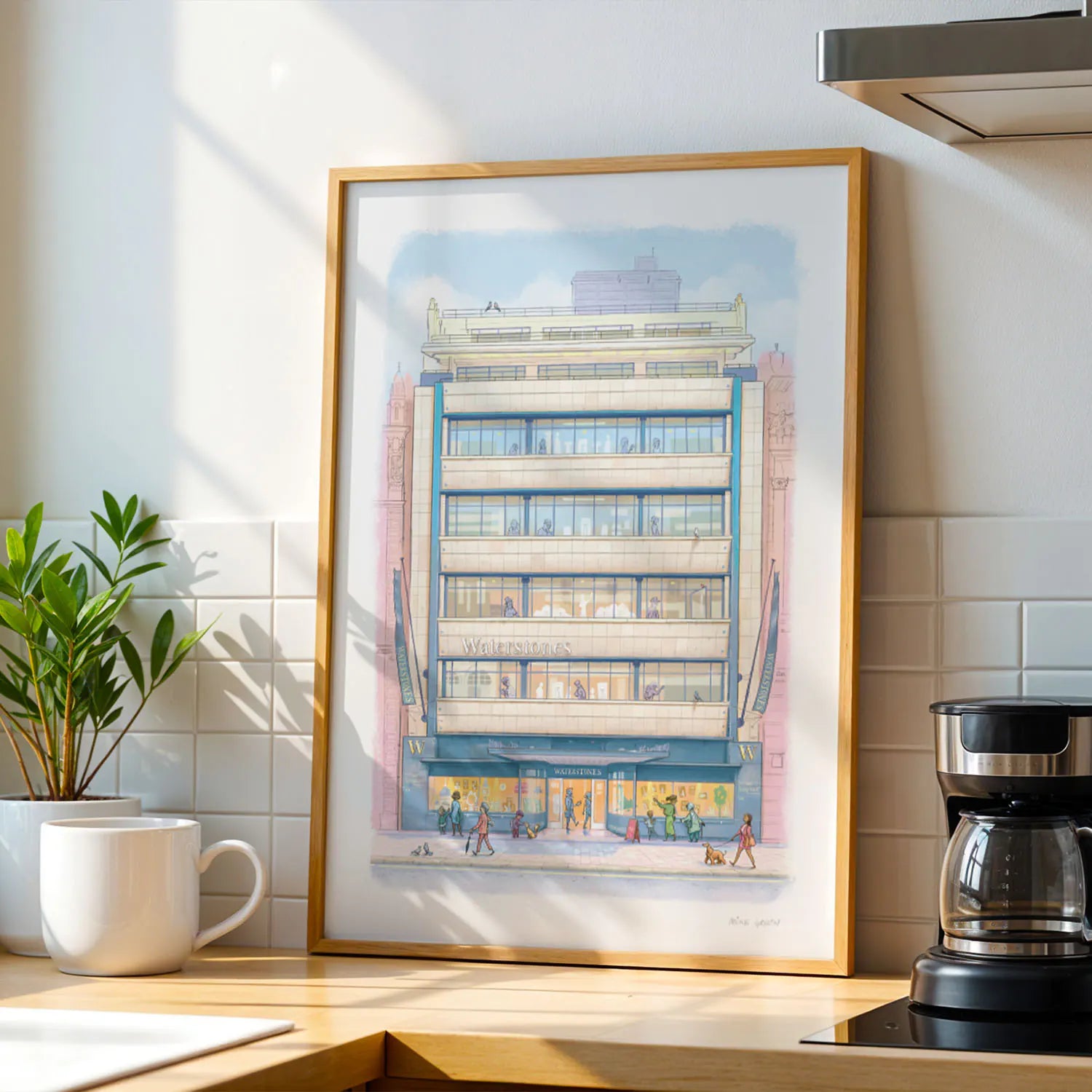 Framed wall art print of Waterstones Piccadilly bookstore in London on a kitchen side with a cup and coffee machine