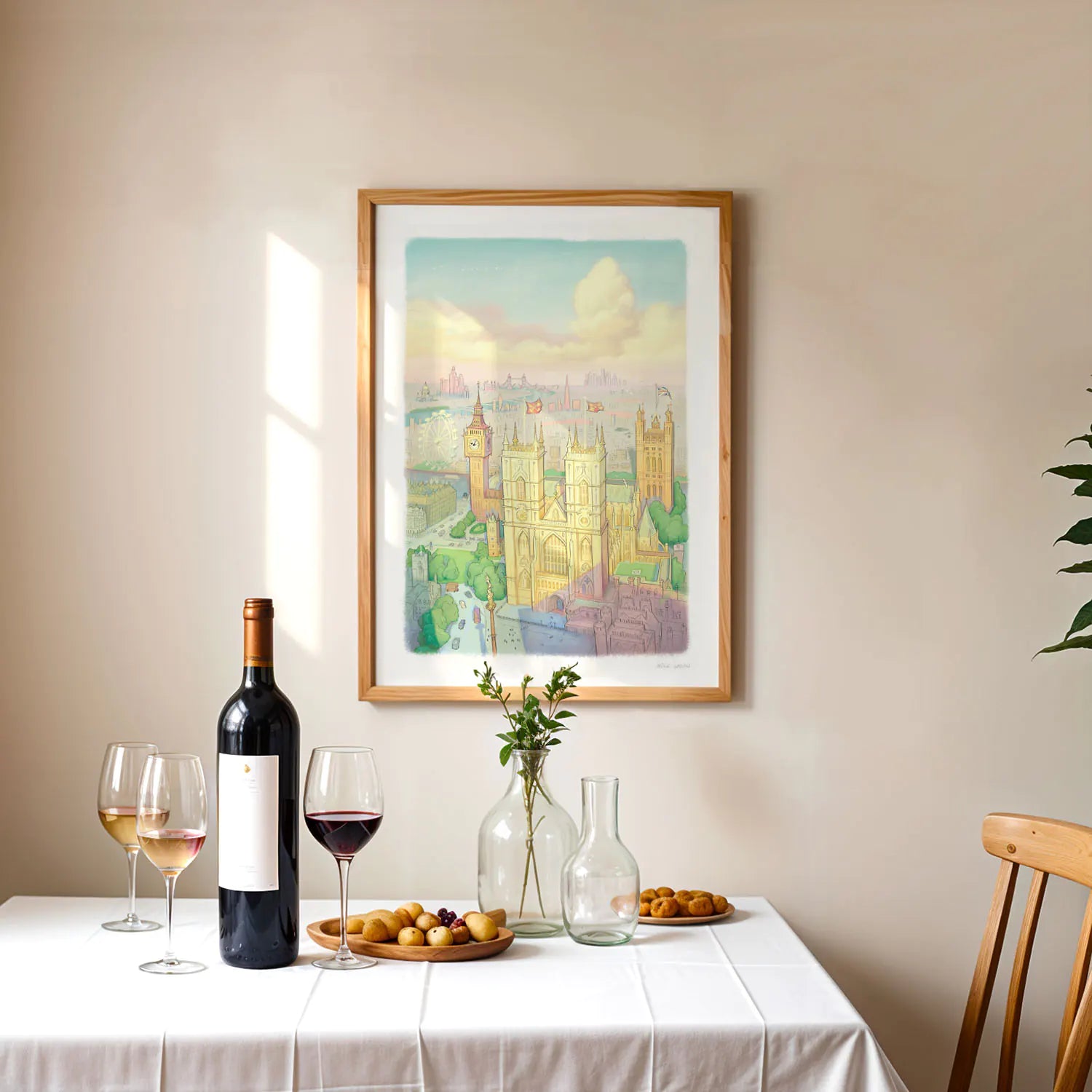 A wall art print of Westminster Abbey in a watercolour illustration style with big ben and the London Eye also shown framed above a able with wine and fruit